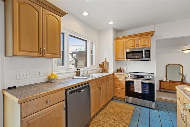 kitchen with dark tile patterned flooring, light brown cabinets, sink, and appliances with stainless steel finishes