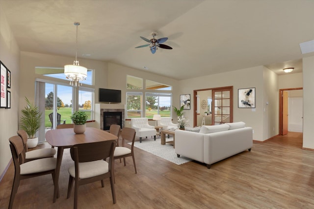 living room with ceiling fan with notable chandelier, light hardwood / wood-style flooring, and lofted ceiling