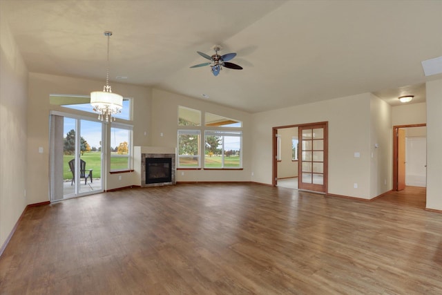 unfurnished living room featuring hardwood / wood-style flooring, ceiling fan with notable chandelier, lofted ceiling, and a high end fireplace