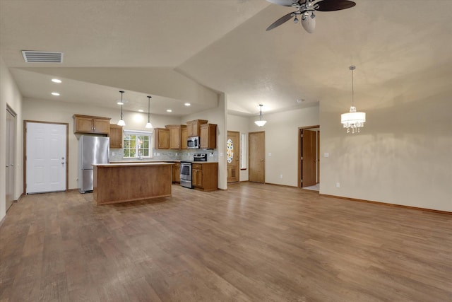 kitchen with decorative backsplash, a center island, stainless steel appliances, and hanging light fixtures