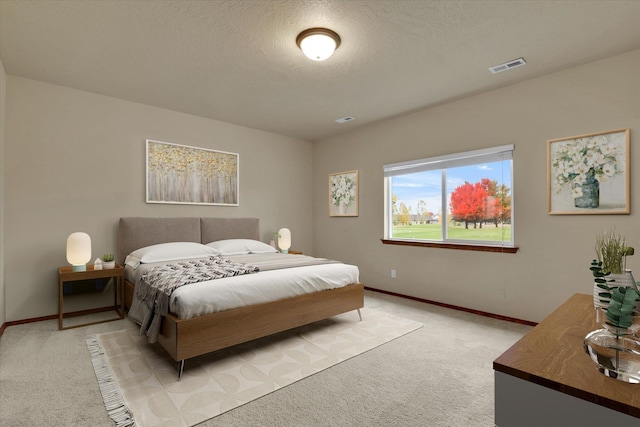 bedroom with light colored carpet and a textured ceiling