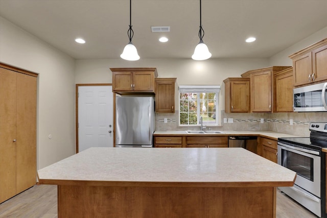 kitchen with sink, backsplash, decorative light fixtures, a kitchen island, and appliances with stainless steel finishes