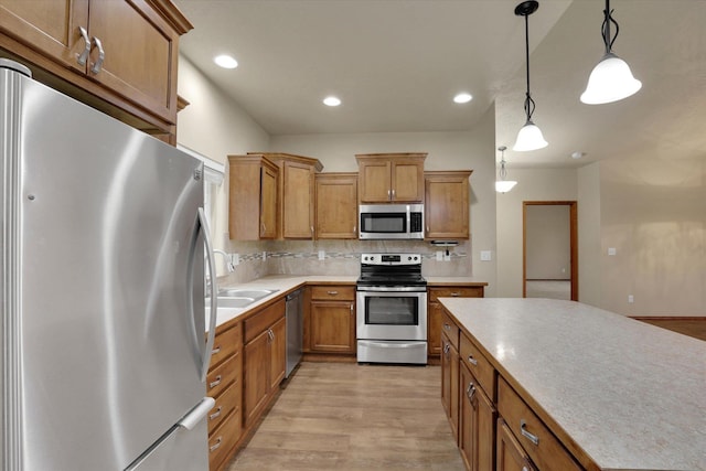 kitchen with sink, hanging light fixtures, decorative backsplash, appliances with stainless steel finishes, and light hardwood / wood-style floors