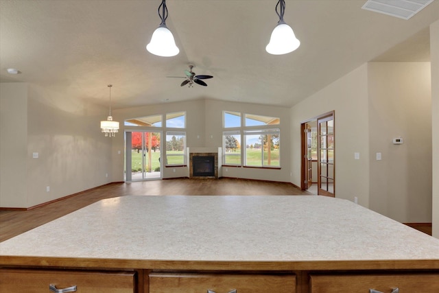 kitchen featuring ceiling fan with notable chandelier, light wood-type flooring, a center island, and hanging light fixtures