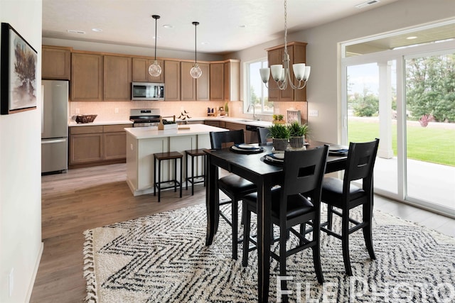 dining space featuring an inviting chandelier, sink, and light hardwood / wood-style flooring