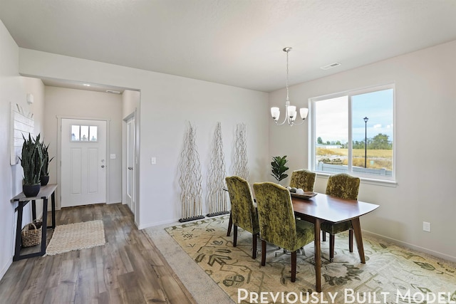 dining area featuring hardwood / wood-style flooring, a textured ceiling, and an inviting chandelier