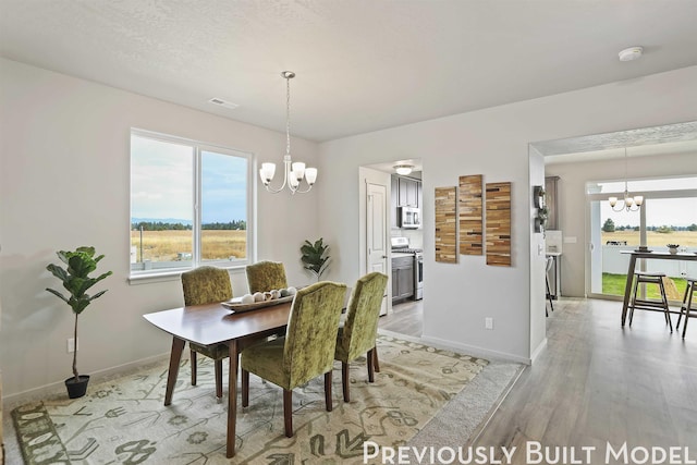 dining space with light hardwood / wood-style floors and an inviting chandelier