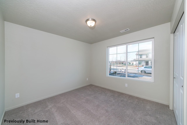 carpeted empty room with a textured ceiling