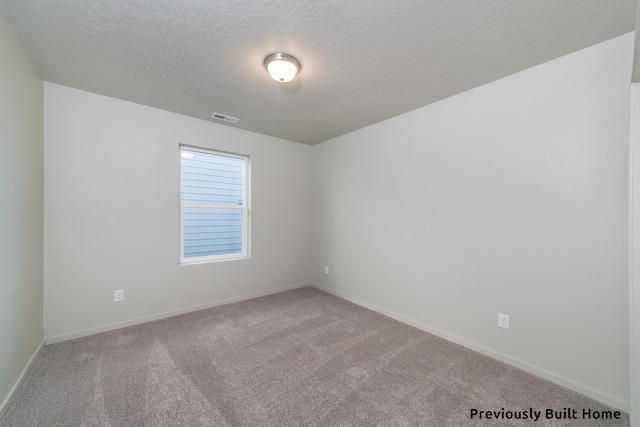 carpeted empty room featuring a textured ceiling