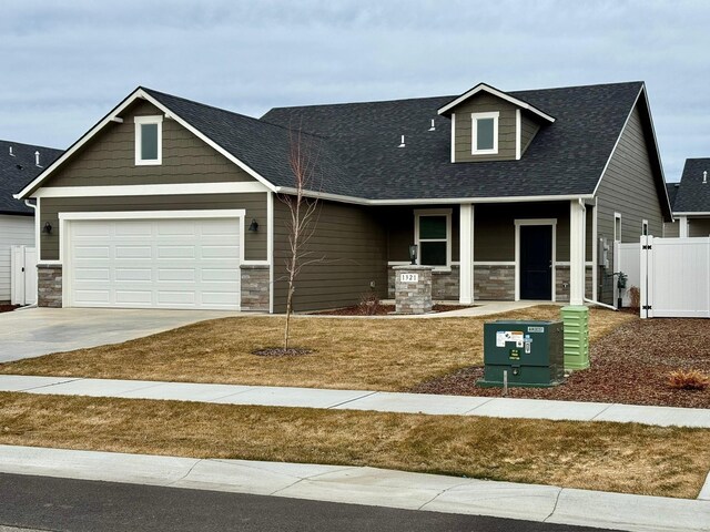 craftsman house with a front yard, a garage, and covered porch