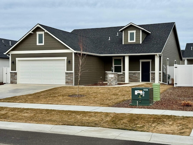 view of front facade featuring covered porch, a gate, fence, a garage, and driveway