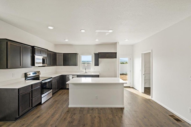 kitchen featuring stainless steel appliances, dark wood-style flooring, visible vents, and a center island