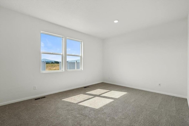 carpeted empty room featuring recessed lighting, visible vents, and baseboards