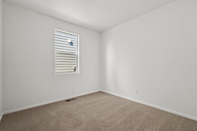 unfurnished room with carpet flooring, visible vents, and baseboards