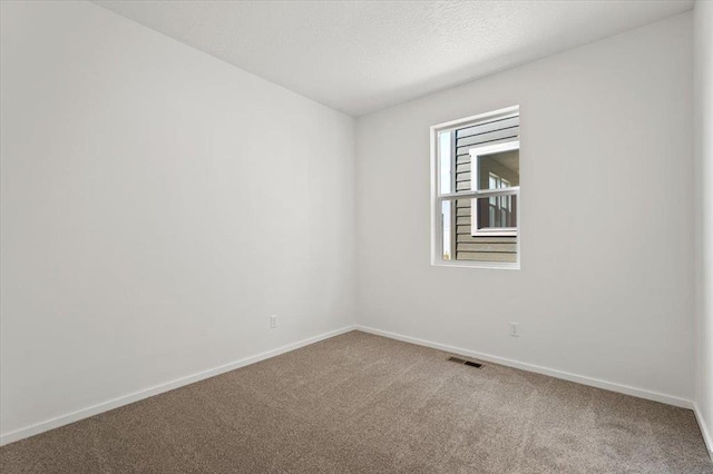 carpeted spare room with visible vents, a textured ceiling, and baseboards