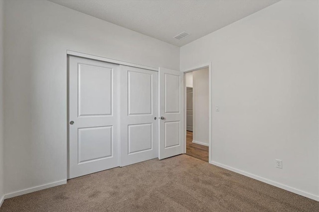 unfurnished bedroom with carpet floors, baseboards, visible vents, and a closet