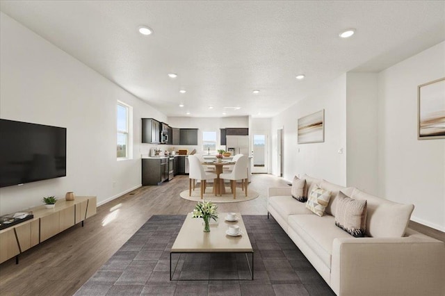 living room featuring a textured ceiling, baseboards, wood finished floors, and recessed lighting