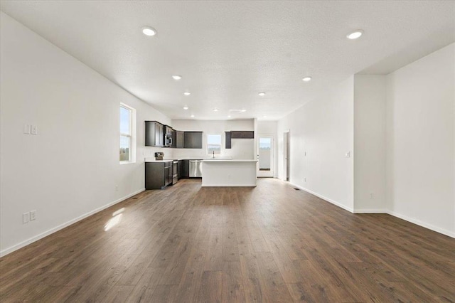 unfurnished living room featuring baseboards, dark wood-style flooring, and recessed lighting