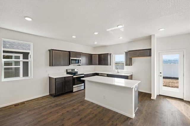 kitchen with stainless steel appliances, light countertops, dark wood-type flooring, a sink, and dark brown cabinetry