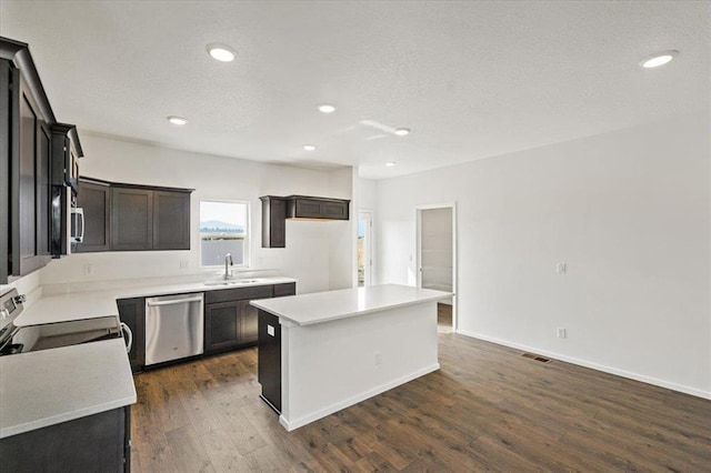 kitchen with visible vents, dark wood finished floors, appliances with stainless steel finishes, a center island, and a sink