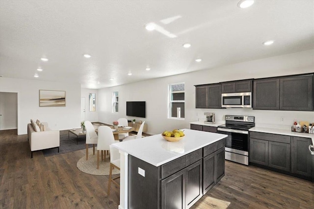 kitchen featuring open floor plan, light countertops, appliances with stainless steel finishes, and dark wood-style flooring