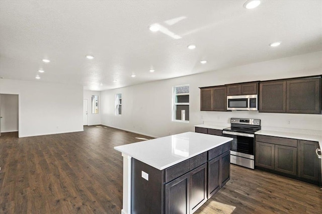 kitchen featuring dark wood finished floors, light countertops, appliances with stainless steel finishes, dark brown cabinetry, and a kitchen island