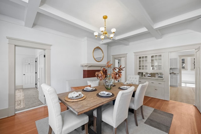 dining room featuring coffered ceiling, beam ceiling, light wood-type flooring, and an inviting chandelier