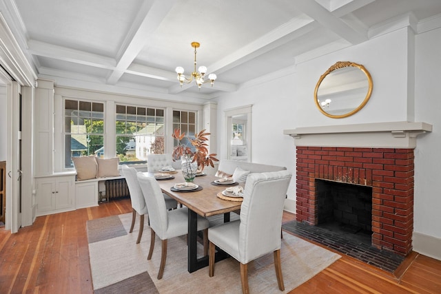 dining room with beam ceiling, coffered ceiling, a brick fireplace, light hardwood / wood-style flooring, and a notable chandelier