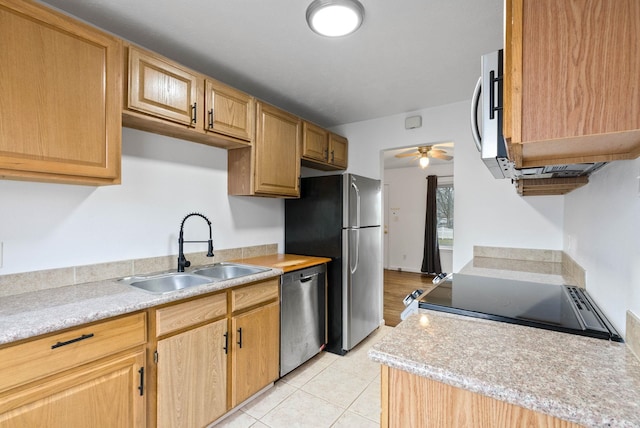 kitchen featuring ceiling fan, sink, light stone counters, light tile patterned flooring, and appliances with stainless steel finishes