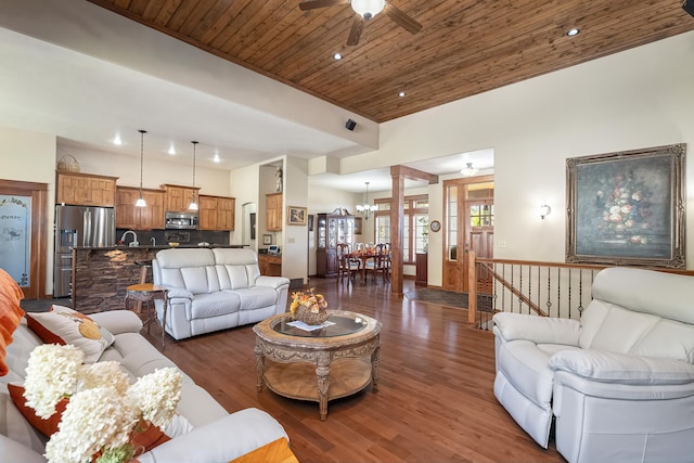 living room featuring decorative columns, dark wood-type flooring, wood ceiling, and ceiling fan with notable chandelier