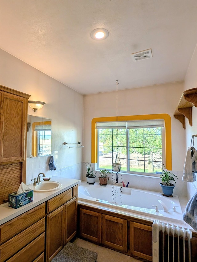 bathroom with radiator heating unit, vanity, and a tub