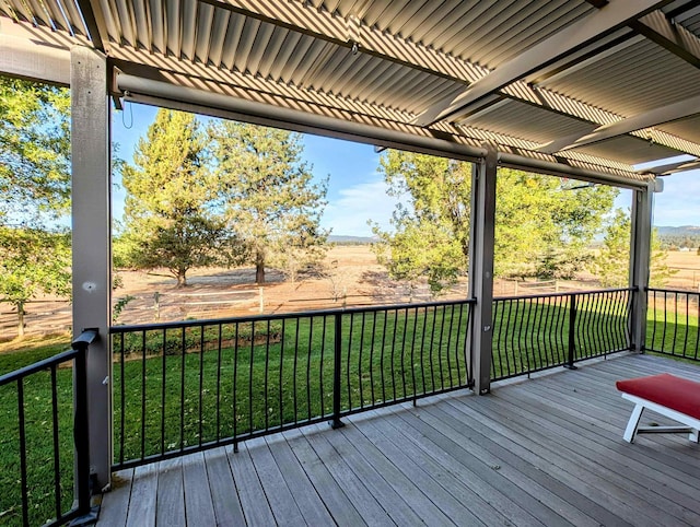 wooden terrace featuring a lawn and a rural view