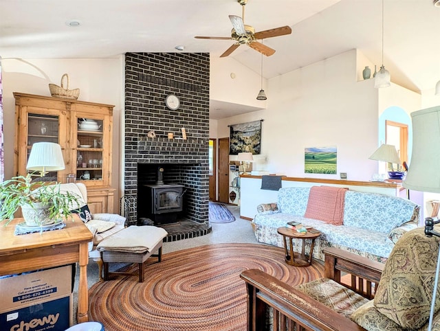 living room featuring ceiling fan, carpet, a wood stove, and high vaulted ceiling