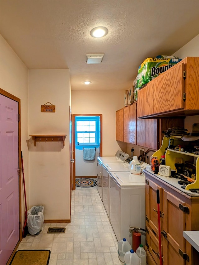 clothes washing area with cabinets, washing machine and dryer, and a textured ceiling