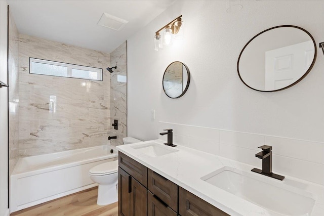 full bathroom with vanity, hardwood / wood-style flooring, tiled shower / bath, and toilet