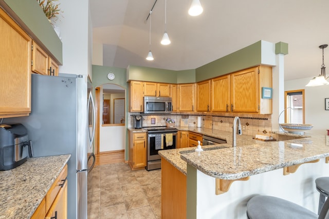 kitchen with kitchen peninsula, light stone countertops, stainless steel appliances, hanging light fixtures, and a breakfast bar area