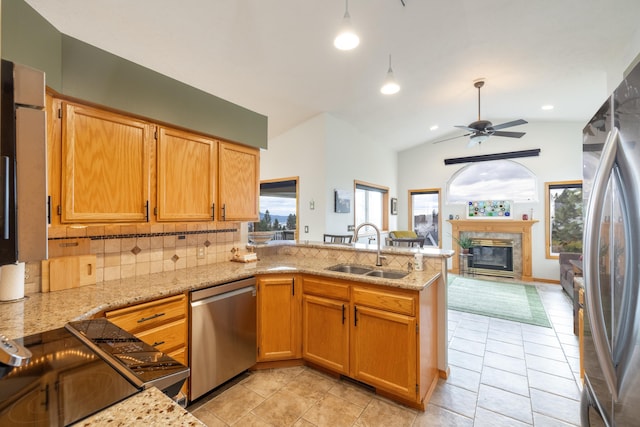 kitchen featuring kitchen peninsula, appliances with stainless steel finishes, decorative backsplash, ceiling fan, and sink