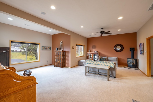 carpeted bedroom featuring ceiling fan and a wood stove