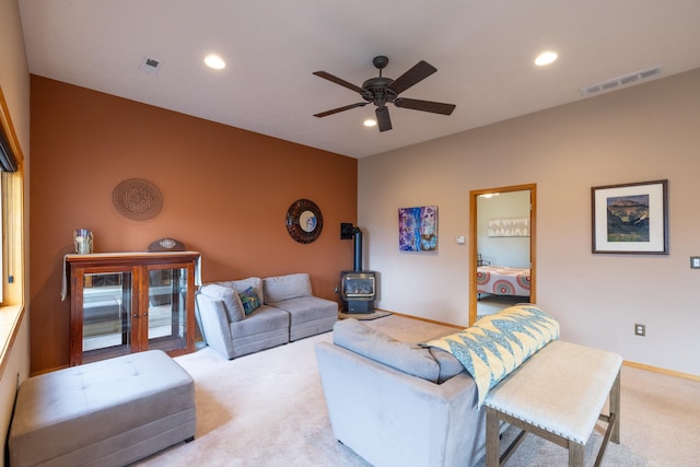 carpeted living room featuring ceiling fan and a wood stove