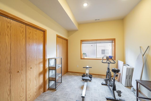 workout area with radiator heating unit and light colored carpet