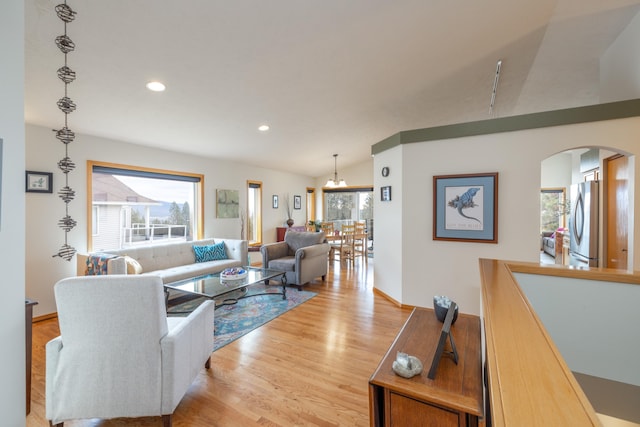 living room with lofted ceiling, light hardwood / wood-style flooring, and a notable chandelier