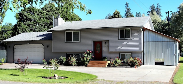 bi-level home featuring a garage, a chimney, a front lawn, and concrete driveway