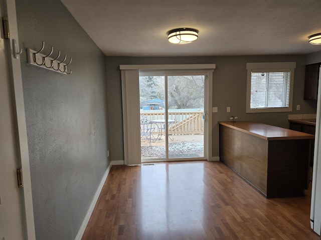 unfurnished dining area with baseboards and wood finished floors