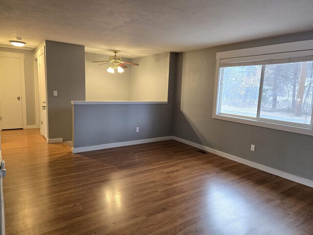 empty room with ceiling fan and dark colored carpet