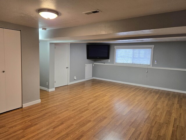 basement featuring a textured ceiling and hardwood / wood-style flooring