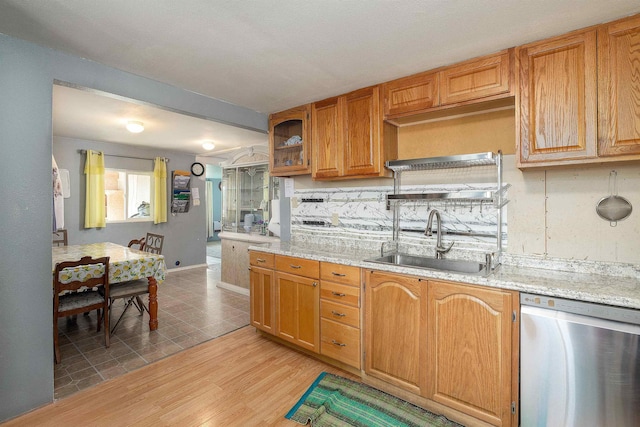 kitchen with light stone countertops, dishwasher, light hardwood / wood-style flooring, and sink