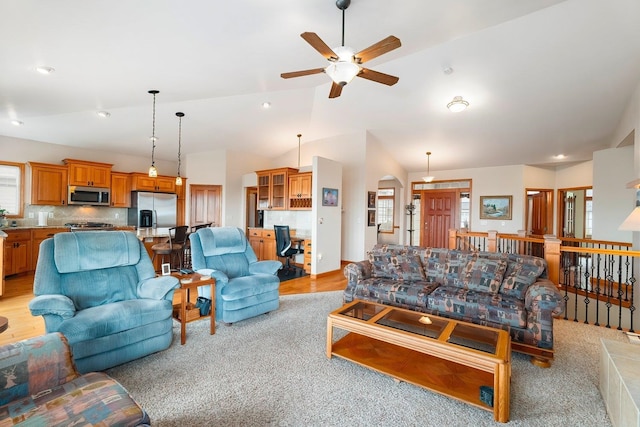 living room featuring ceiling fan, light carpet, and vaulted ceiling