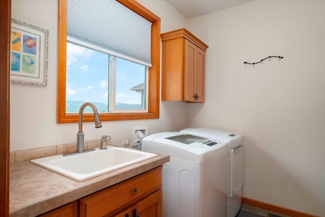 laundry room featuring washer and clothes dryer, sink, and cabinets