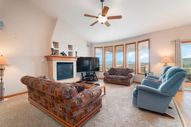 living room featuring ceiling fan, a fireplace, wood-type flooring, and vaulted ceiling