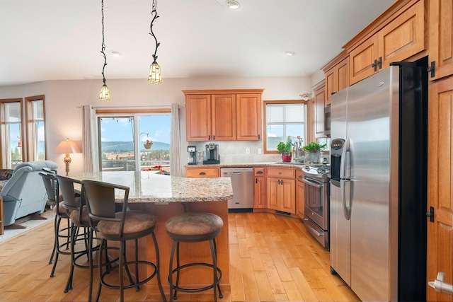 kitchen with tasteful backsplash, a breakfast bar, stainless steel appliances, a kitchen island, and hanging light fixtures